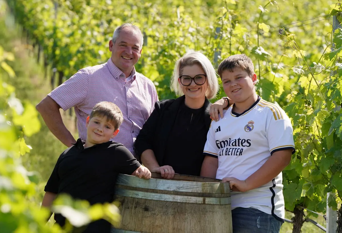 Rainer und Nicole Dieroff mit ihren beiden Söhnen an einem Holzfass zwischen den Rebzeilen.