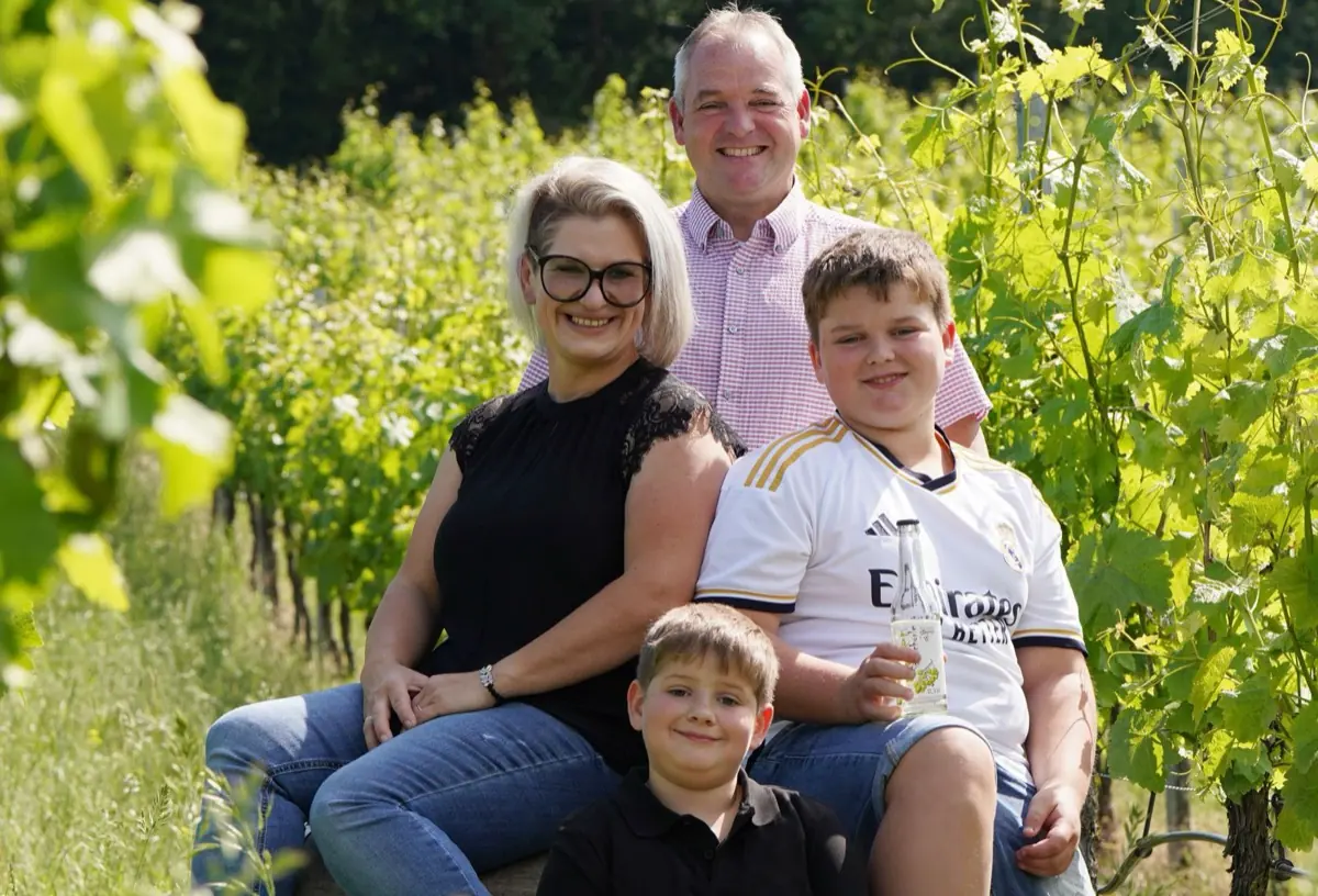 Die Familie Dieroff sitzt in einer Rebzeile, ein Sohn hält eine Flasche Traubensaftschorle.