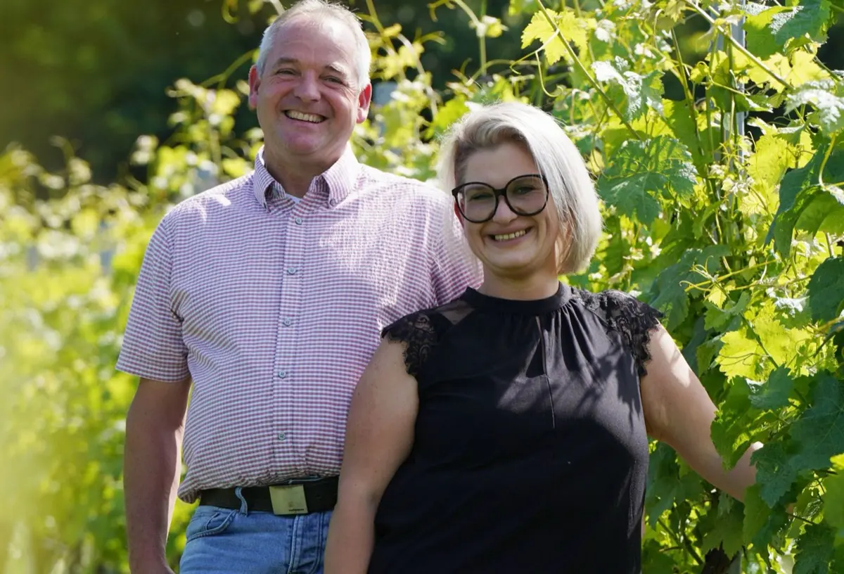 Rainer und Nicole Dieroff stehen lächelnd nebeneinander in einer Rebzeile.